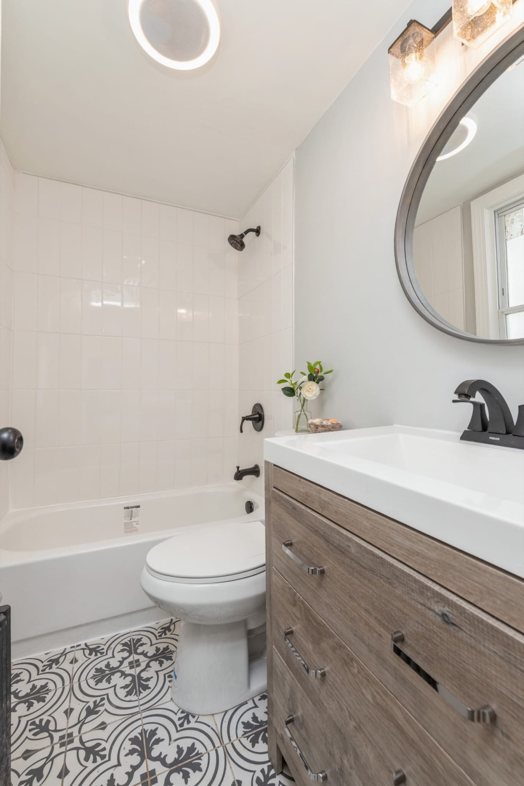 Bathroom with patterned tile floor, wood vanity and matte black fixtures