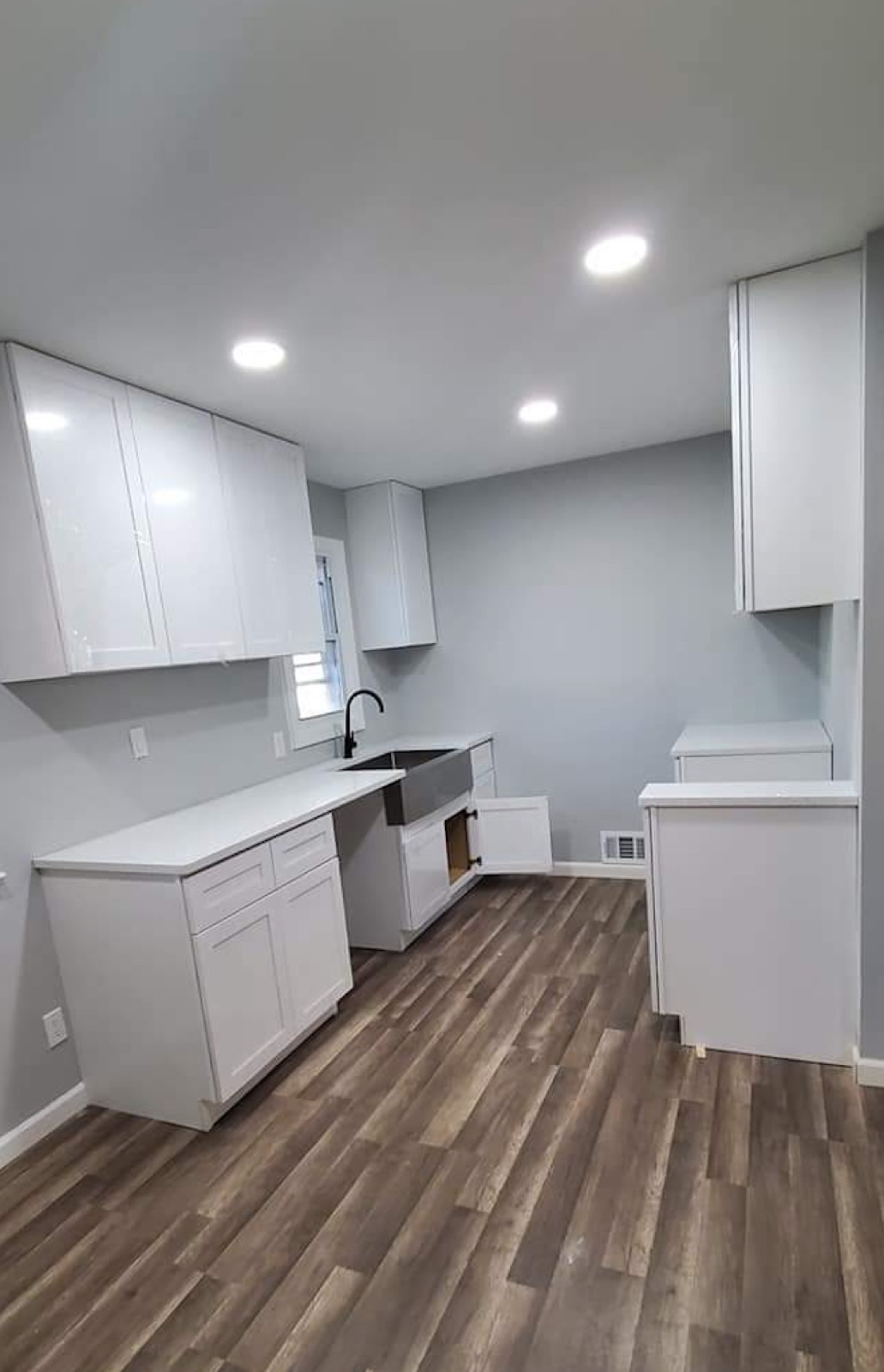 Newly built white kitchen with a farmhouse sink and wide plank flooring