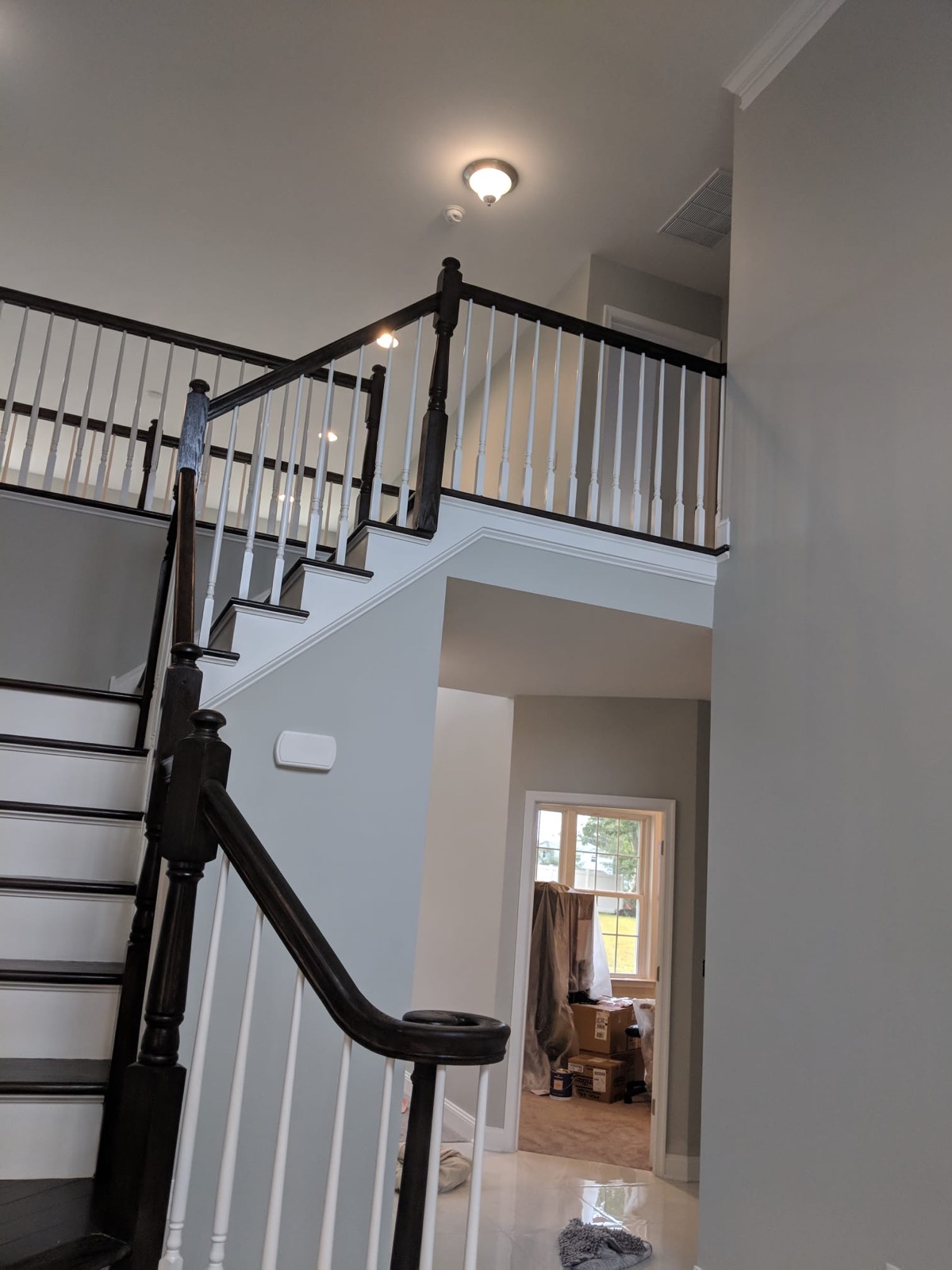 Staircase with dark handrails and white balusters in a two storey entry